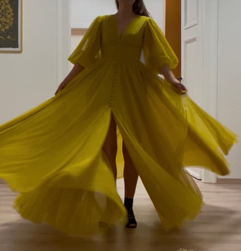 Reviewer twirling in the Canary Yellow Starlight Draped Gown, showing the full skirt and leg slit.