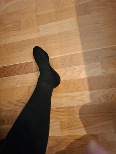 Recensent som visar passformen av en svart Diasocks stödstrumpa på sitt ben.