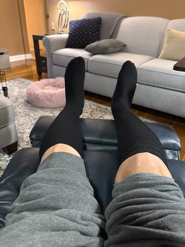 Reviewer's first-person view of their legs propped up, wearing the black Performance Eucalyptus Compression Socks.