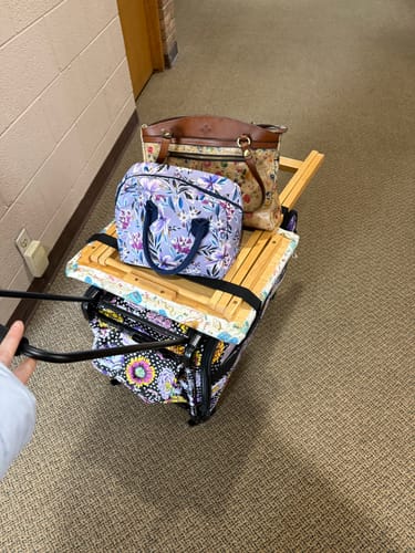 Customer pulling the Kaffe Fassett Big Blooms Sewing Machine Trolley, stacked with several other bags and items.