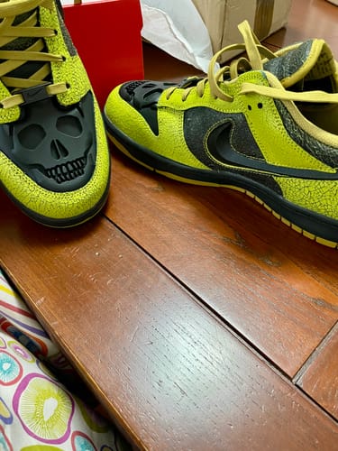 Recensent toont een close-up van de Nike Dunk Low QS Halloween Skull-sneakers in een opvallende groene en zwarte kleur.