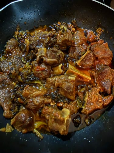 Close-up of a reviewer's rich curry made with Halal Goat Cubes and bitter melon in a pan.