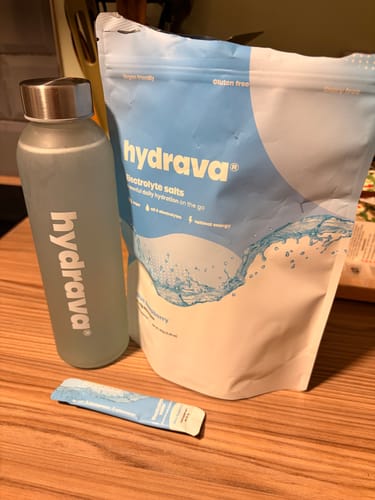 Customer's Electrolyte Salts sample pack pouch, a single sachet, and a branded water bottle on a wooden table.