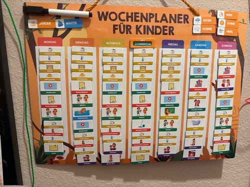 Kundenfoto des magnetischen Wochenplaners von Edubini, der an der Wand hängt und mit Aktivitätsmagneten für die ganze Woche gefüllt ist.