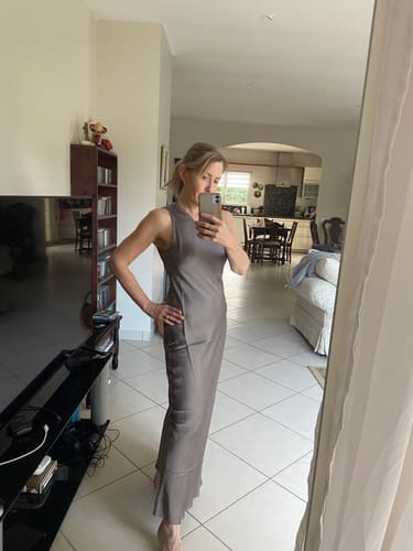 Customer takes a mirror selfie wearing the long, mink Sabrina Sleeveless Satin Dress.