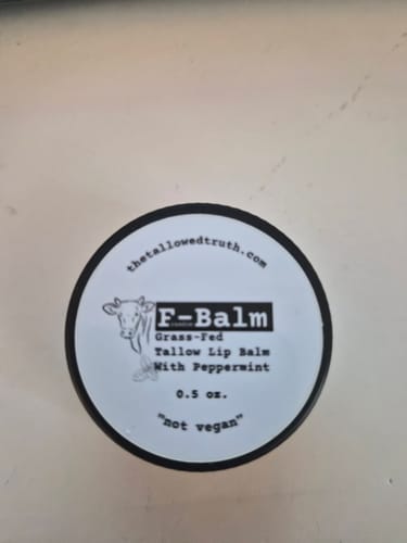 Customer's top-down view of the F-Balm Tallow Lip Balm in its small black tin.