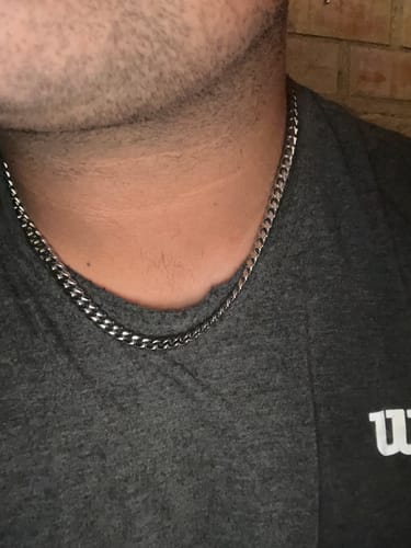 Primer plano de un cliente que lleva la Cadena Cuban Link de 8 mm en el cuello sobre una camiseta gris.