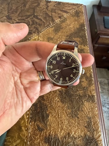 Cliente sosteniendo en su mano el reloj Laco Genf2, que tiene una esfera oscura y una correa de cuero.