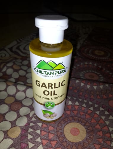 Customer's bottle of Chiltan Pure Garlic Oil with a white cap, standing on a patterned surface.