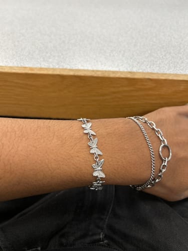 Reviewer wearing the silver Butterfly Bracelet on their wrist, styled next to another chain bracelet.