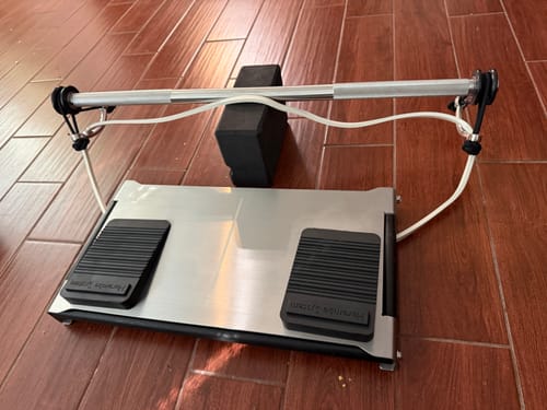 Reviewer's stainless steel CyberPlate set up with a resistance band and bar on a wooden floor.