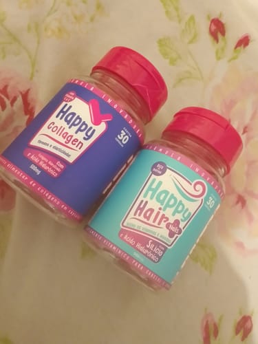 Cliente exibe os potes dos suplementos Happy Hair e Happy Collagen sobre uma superfície com estampa floral.