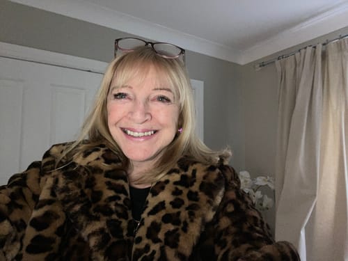 Close-up of a reviewer smiling while wearing the brown leopard print faux fur coat.