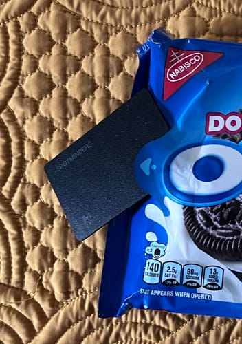 Reviewer showing the SPOTMINDERS. Tracking Card tucked into a package of cookies on a quilted surface.