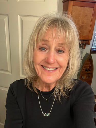 Reviewer smiling while wearing her Leaves Green Onyx Necklace layered with a shorter silver necklace.