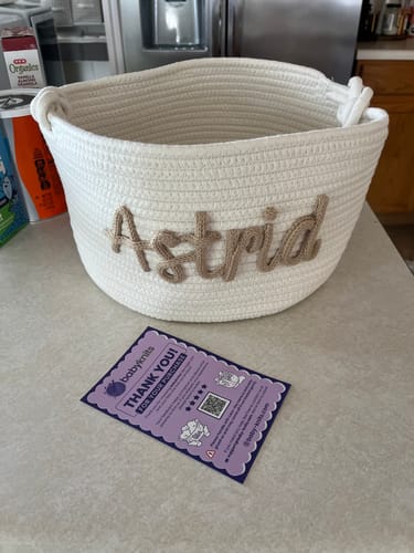 Customer's personalized woven basket with the name "Astrid" in beige cursive on a kitchen counter.