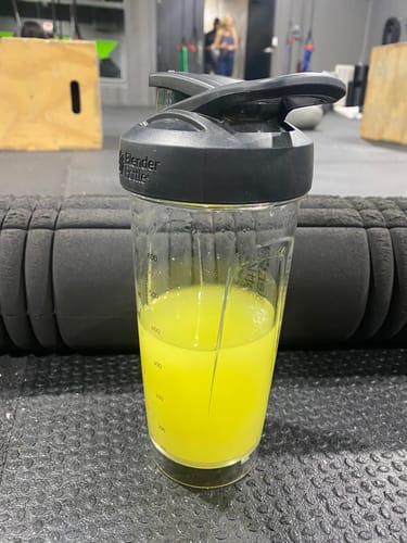 Customer's yellow Pre Workout drink mixed in a clear shaker bottle on a gym floor.