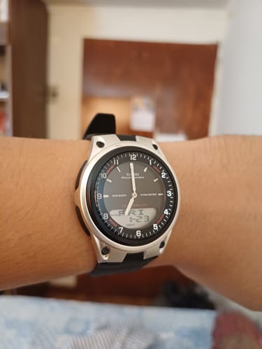 Un cliente muestra el reloj Casio Análogo-Digital Vintage en su muñeca. El reloj tiene una caja plateada y una correa negra.