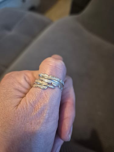 Close-up of a reviewer's thumb with the silver Feather From An Angel Ring wrapped around it.