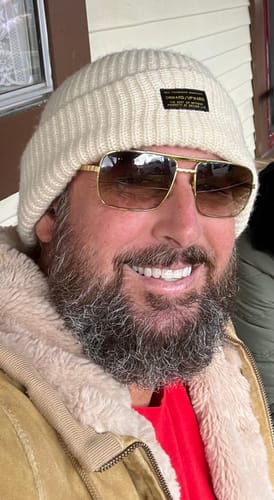 Customer smiling while wearing a ribbed cream Big Fisherman Beanie outdoors.