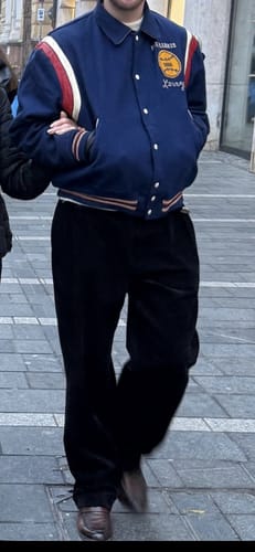 Reviewer showing the fit of the black Double Pleated Corduroy Trousers while walking down a street.