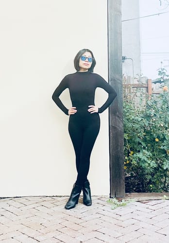 Customer posing outdoors in the black, form-fitting NW Sculpt Jumpsuit.