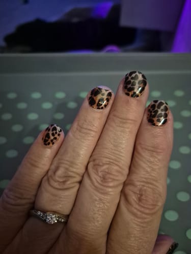 Close-up of a reviewer's hand showing a leopard print manicure from the Deluxe Gift Set.