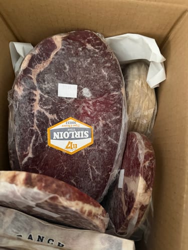Cliente mostrando el Kit Carne Asada envasado al vacío dentro de una caja de cartón.