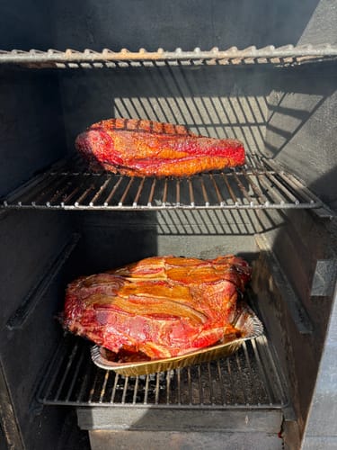 Customer's smoked brisket and deer quarter cooking on two racks in a smoker after using the Reserve Blend Brisket Injection.