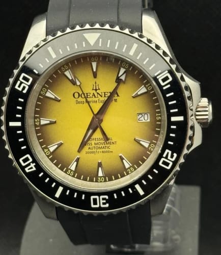 Reviewer's close-up of the Oceaneva automatic watch, highlighting its yellow burst dial and black ceramic bezel.