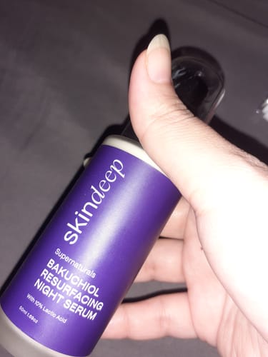 Customer holding the purple bottle of Bakuchiol Resurfacing Night Serum, showing the product label.