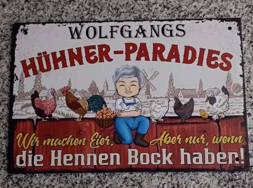 Rezensent zeigt sein personalisiertes Gartenschild mit lustigem Hühnermotiv und der Aufschrift 'Wolfgangs Hühner-Paradies'.