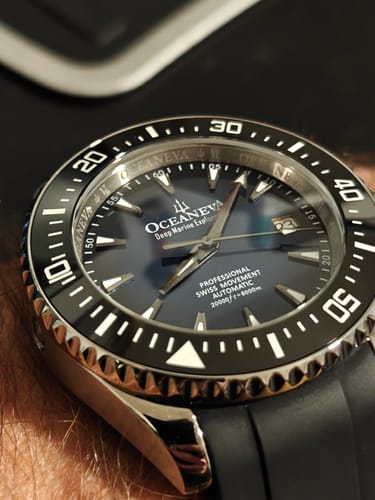 Customer's close-up view of the Oceaneva Deep Marine Explorer VI watch. The deep blue dial and black bezel are on their wrist.