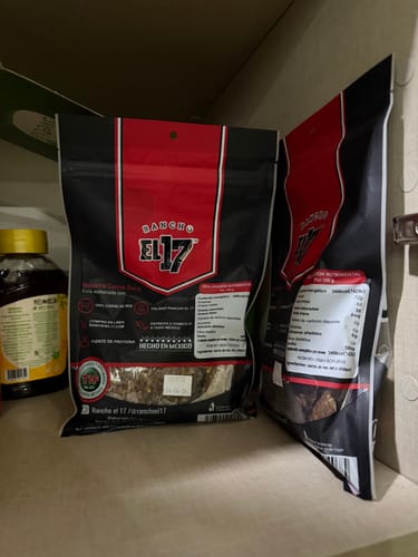Cliente muestra dos bolsas de Carne Seca con Chile en una alacena.