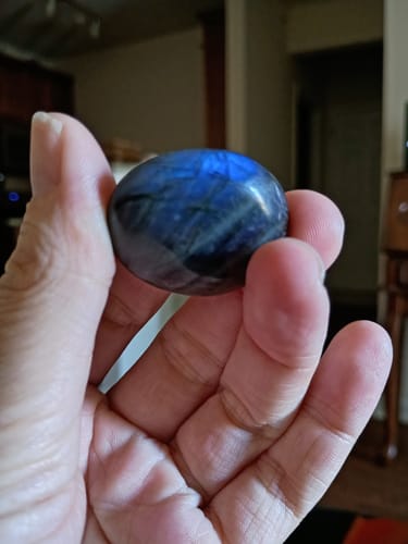 Reviewer holding an iridescent blue labyrite moonstone from the VIP Crystal Club in their hand.