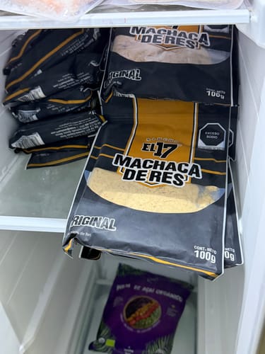 El cliente muestra varias bolsas de Machaca de Res apiladas en un congelador.