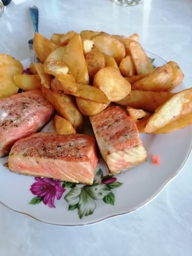 Farfuria unui client cu file de somon și cartofi aurii, gătiți cu friteuza Novio StonePro.