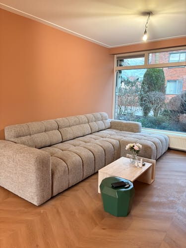 Recensent toont de Salontafel MEMO met travertijneffect in een woonkamer voor een bank.