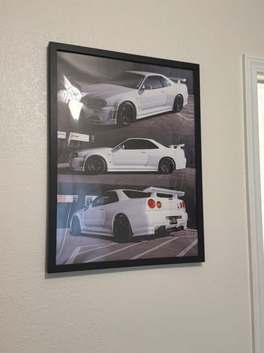 Customer's TCG90 R34 GT-R poster, framed in black and hanging on a wall.