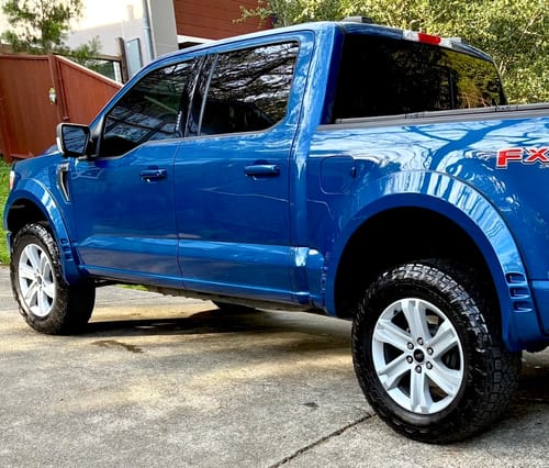 Customer's blue F150 truck from the side, showing the wider stance created by the 1.5 inch wheel spacers.