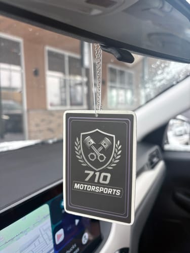 A customer's custom air freshener with a "710 Motorsports" logo hanging from a car's rearview mirror.