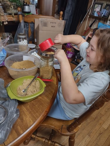 Customer shows a child using the stainless steel funnel to pour ingredients from a red cup into a glass jar.