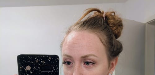 Eine Kundin zeigt ihre Wimpern nach der Anwendung des persönlichen Starter-Kits.