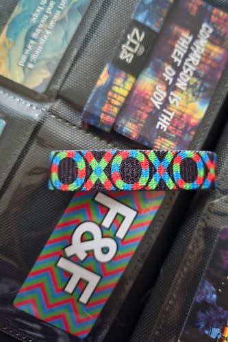 Close-up of a customer's colorful Spectra Interactive Bracelet and its F&F collector's card in a display binder.