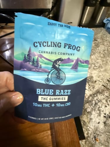 Reviewer holding the blue pouch of Cycling Frog Blue Razz THC Gummies.