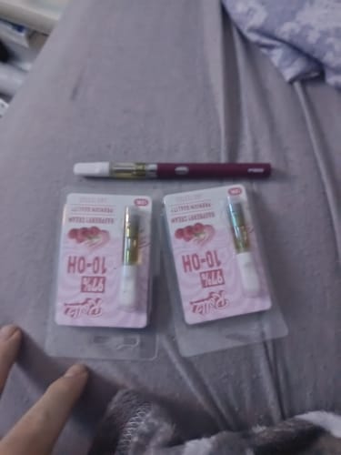 Customer's purple ROLLZ 510 Thread Cartridge Battery with two new cartridges in their packaging on a bedspread.