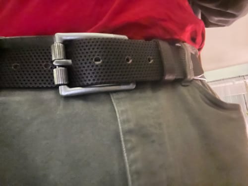 Close-up of a reviewer wearing the black Legend Double Prong Retro Style belt with green pants and a red shirt.