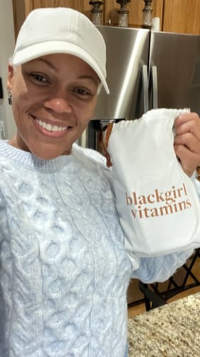 A smiling reviewer holds a white 'blackgirl vitamins' drawstring bag for their BGV Collagen Powder.