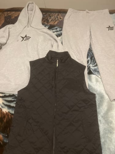 Customer's Lifestyle Bundle laid out, showing the light grey fleece hoodie and joggers, and a black quilted vest.