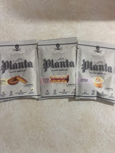 Customer showing three Planta single-serving protein packets in Peanut Butter Cup, PB & Jelly, and Sprinkle Cupcake flavors.